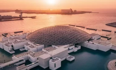 قبة اللوفر أبوظبي المميزة وسط ضوء الشمس المتسلل.