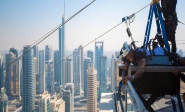 مغامر يستمتع بتجربة إكس لاين دبي مارينا مع خلفية ناطحات السحاب.