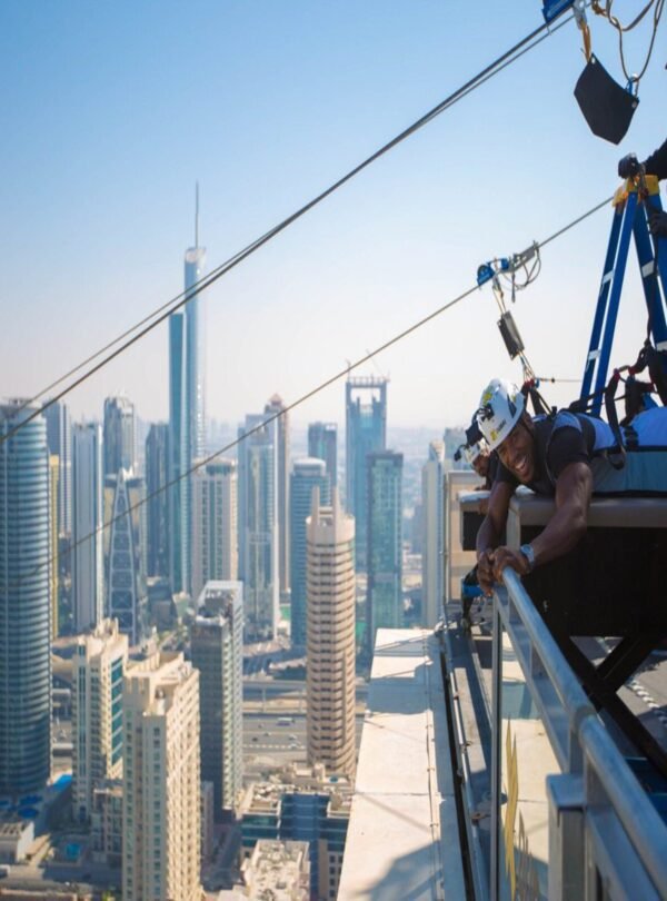مغامر يستمتع بتجربة إكس لاين دبي مارينا مع خلفية ناطحات السحاب.